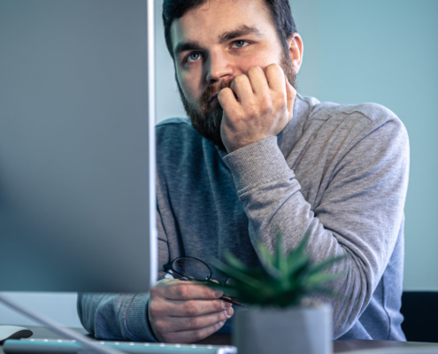 Tired bearded man looks at the computer screen.